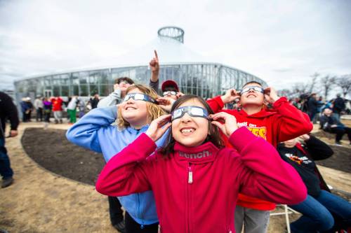 MIKAELA MACKENZIE / FREE PRESS
                                Kara Ritchot (centre, eight) and her cousins look through their eclipse glasses at the solar eclipse viewing party at The Leaf in Assiniboine Park on Monday, April 8, 2024. For Nicole story.