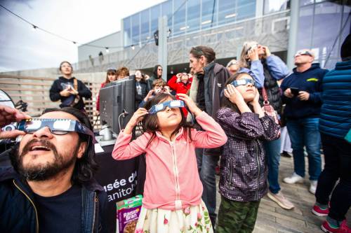 MIKAELA MACKENZIE / FREE PRESS
                                Rafael (left), Isabel (six), and Gabriel (eight) Reyes look through their eclipse glasses at the solar eclipse viewing party at The Leaf in Assiniboine Park on Monday, April 8, 2024. For Nicole story.