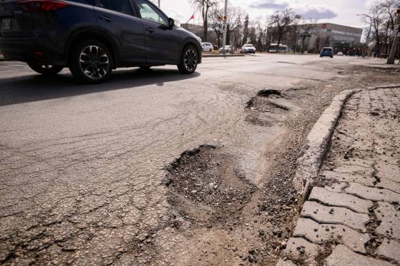 Drivers avoid the long line of potholes at the corner of Broadway and Memorial Blvd Friday afternoon. (Mike Sudoma / Free Press)