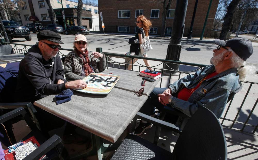 Tim Brandt, Di Harms, and Les Brandt enjoy the spring weather with some Scrabble on a Corydon Avenue patio. (John Woods / Free Press)