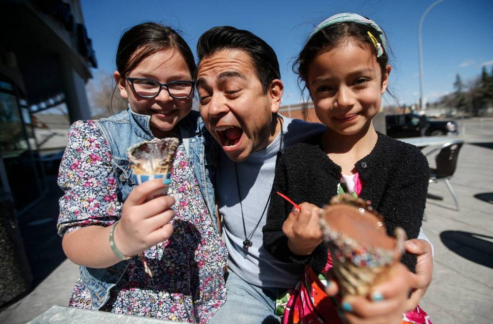 Eduardo Morales and daughters Julieta, left, and Giada enjoy some ice cream and the spring weather on Corydon Avenue Sunday afternoon. (John Woods / Free Press)