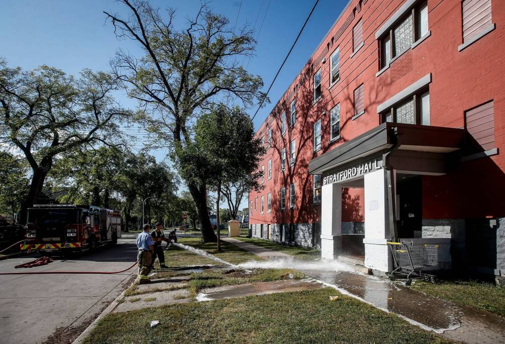 Firefighters wash off the blood on the pavement after a killing outside an apartment block at 285 College Ave. in September. He later died of his injuries. (John Woods / Free Press files)