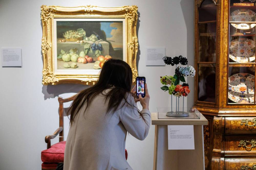 Joëlle Preston with Oliva + Olga takes a photo of her arrangement, which goes with the painting Still Life with Fruit by Luis Meléndez. (Mike Deal / Free Press)