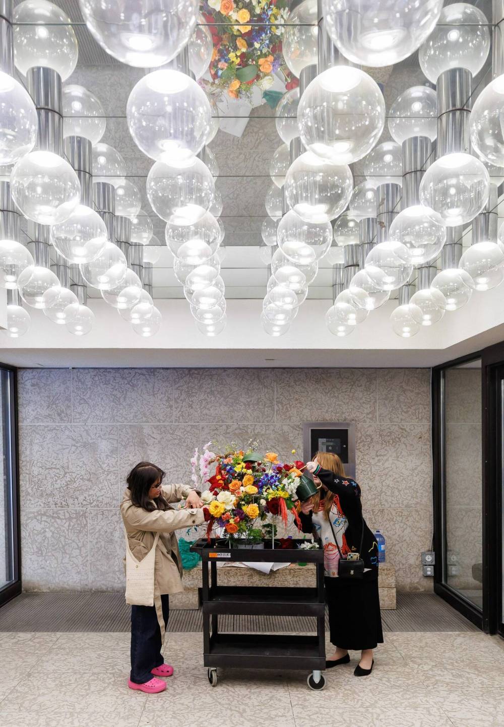 Aira Villanueva (left) brings her arrangement into the WAG-Qaumajuq and checks it over with help from volunteer Leonie Stranc). (Mike Deal / Free Press)