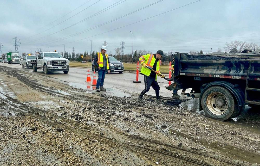 Ruth Bonneville / Free Press
City crews fill in a large pothole after several vehicles got flat tires hitting it Monday. The gaping crater was in the right-hand lane along Bishop Grandin Blvd. just east of River Road.