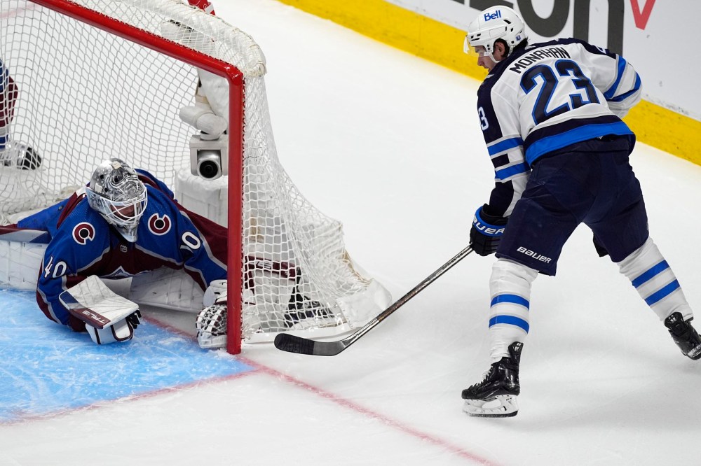 Alexandar Georgiev (left) stops a wraparound shot by Sean Monahan during the first period Friday in Denver. (David Zalubowski / The Associated Press)
