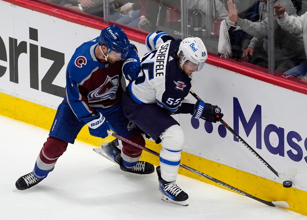 Mark Scheifele tries to control the puck next to Avalanche defenceman Devon Toews during the first period Friday in Denver. (David Zalubowski / The Associated Press)