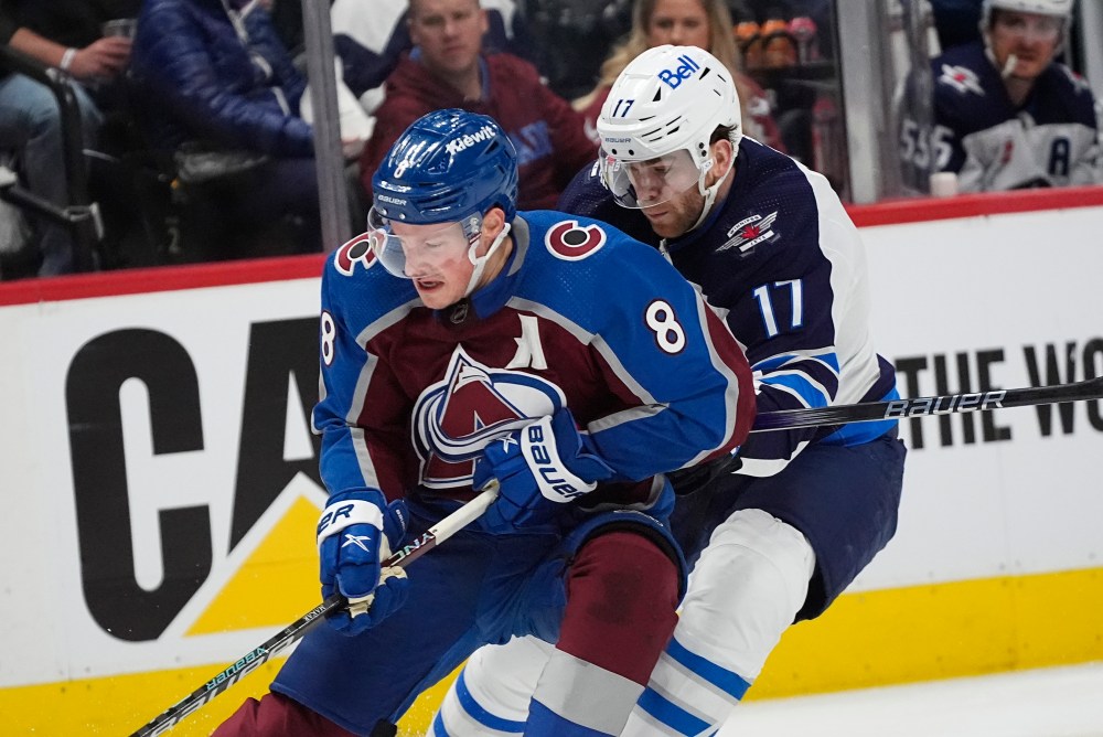 Colorado Avalanche defenseman Cale Makar, left, collects the puck with Winnipeg Jets center Adam Lowry, right, in pursuit in the second period. (David Zalubowski / The Associated Press)
