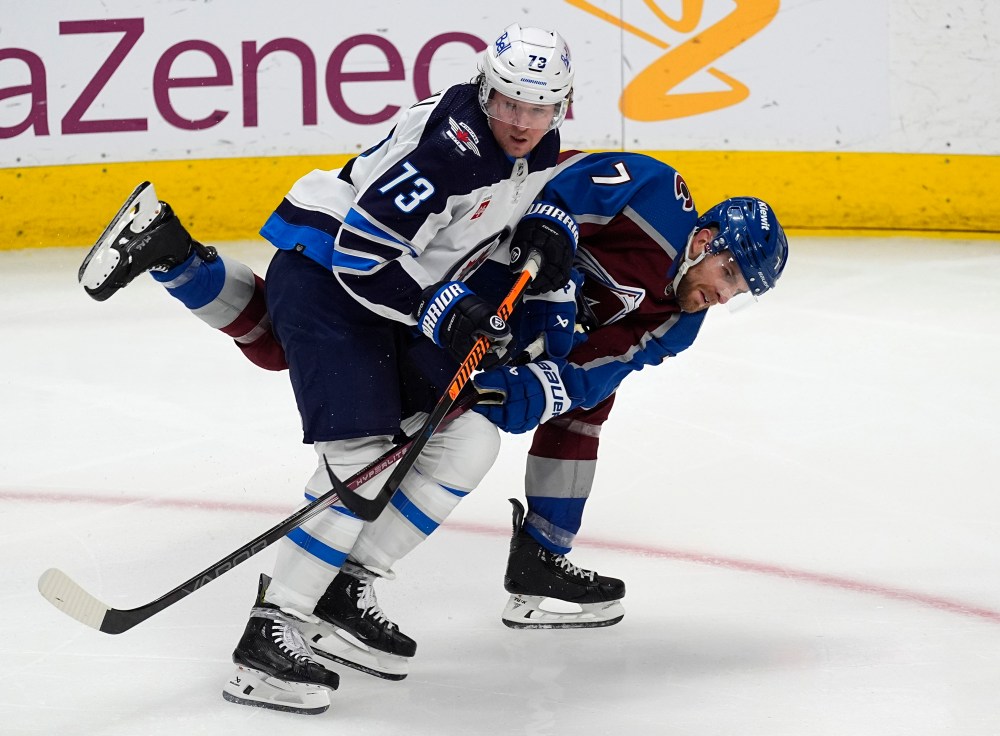 Winnipeg Jets centre Tyler Toffoli, left, checks Colorado Avalanche defenseman Devon Toews, right, in the third period. (David Zalubowski / The Associated Press)