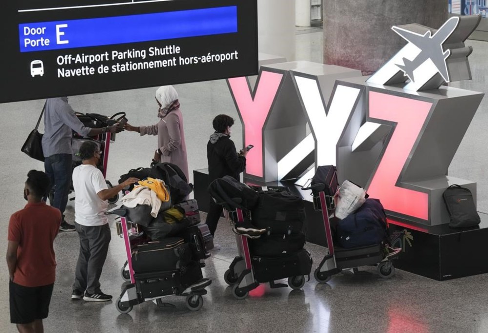People wait with their luggage at Pearson International Airport in Toronto on Friday, August 5, 2022. A ruling from the Canadian Transportation Agency says that a couple who called to cancel their booking on a flight that had already been cancelled by the airline means they are not entitled to a refund. THE CANADIAN PRESS/Nathan Denette