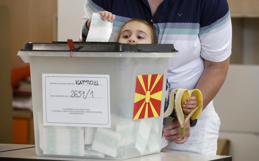 A girl casts the ballot of an adult during the parliamentary election and the presidential runoff, at a polling station in Skopje, North Macedonia, on Wednesday, May 8, 2024. Voters in North Macedonia go to the polls Wednesday for a double election — parliamentary and presidential — following a campaign in which the country's aspirations to join the European Union have played a central role. (AP Photo/Boris Grdanoski)