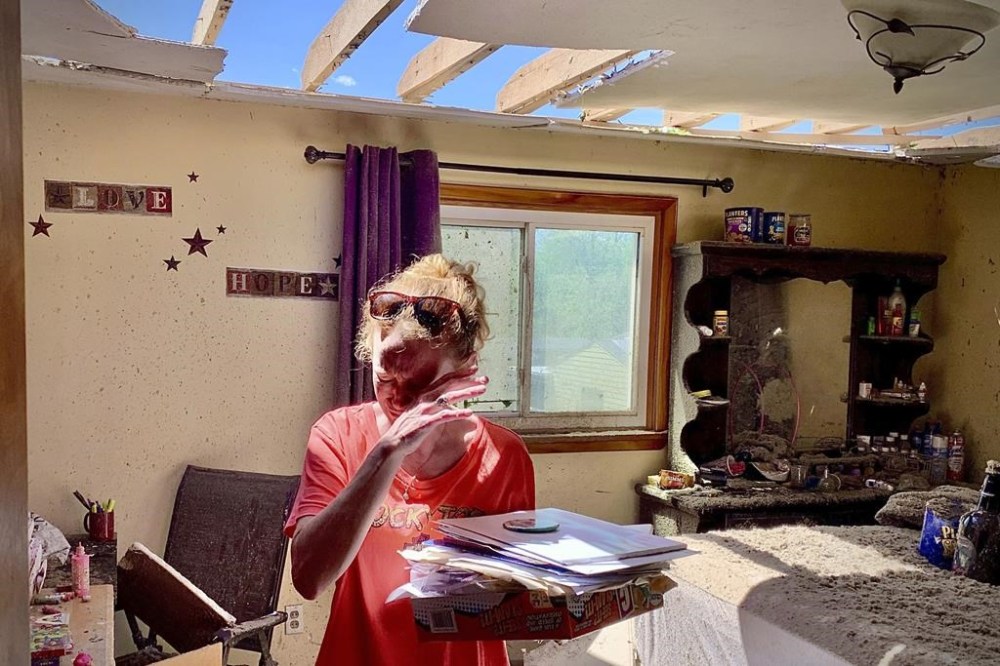 Greenville, Ohio, resident Brenda Pollitt wipes the tears from her eyes as she removes important papers from her bedroom, Wednesday, May 8, 2024. Pollitt and her children were home at the time of the strong storm that hit Tuesday evening, May 7. She and her family ran downstairs and were all safe. (Marshall Gorby/Dayton Daily News via AP)