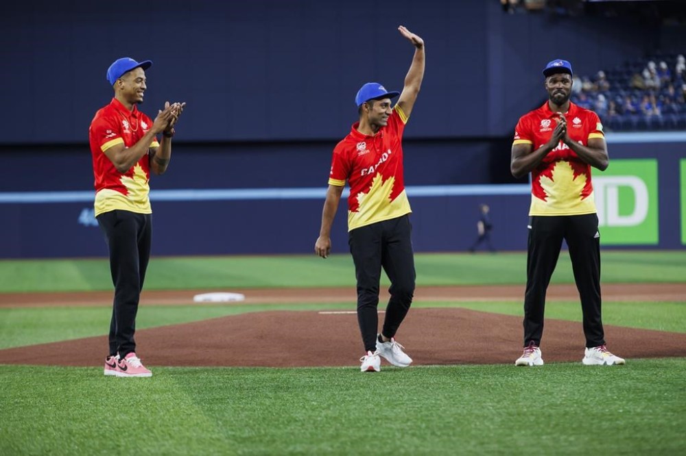 Canadian cricket team captain Saad Bin Zafar waves as he's flanked by teammates Nicholas Kirton, left, and Jeremy Gordon, right, after throwing out the first pitch at the Toronto Blue Jays game against the Minnesota Twins in Toronto on Friday, May 10, 2024. THE CANADIAN PRESS/Cole Burston