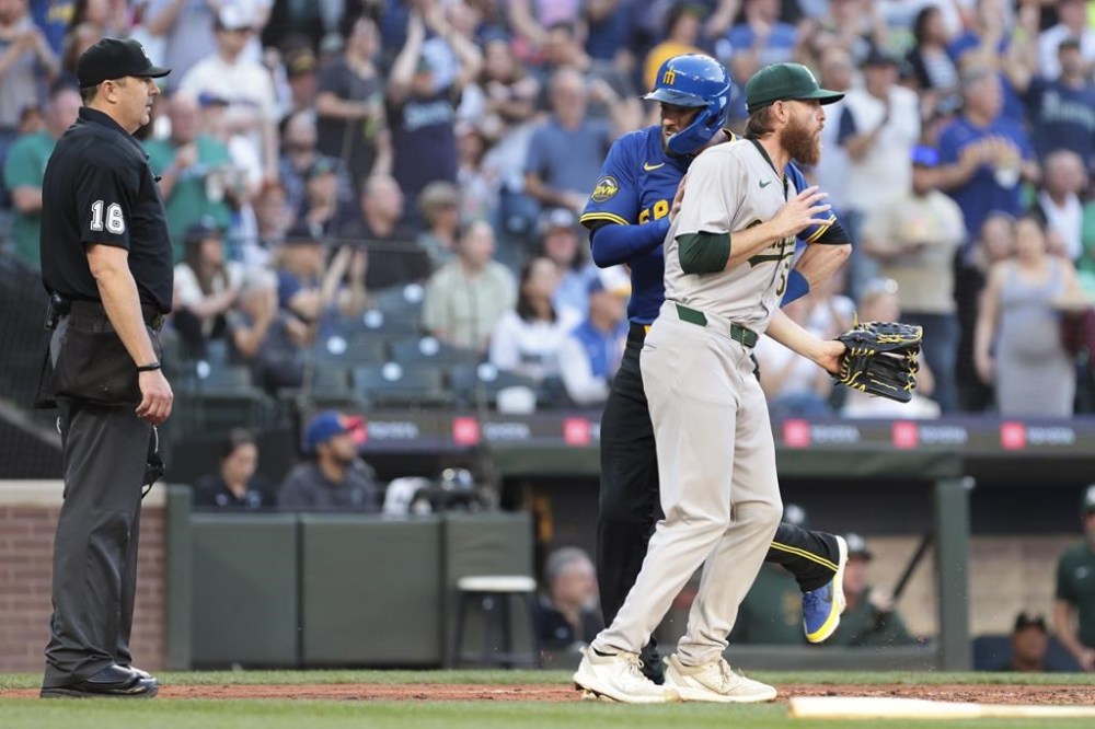 Seattle Mariners' Mitch Haniger, second from left, runs into Oakland Athletics pitcher Paul Blackburn, right, as he crosses home plate on a double by Luke Raley during the fourth inning of a baseball game, Friday, May 10, 2024, in Seattle. (AP Photo/Jason Redmond)
