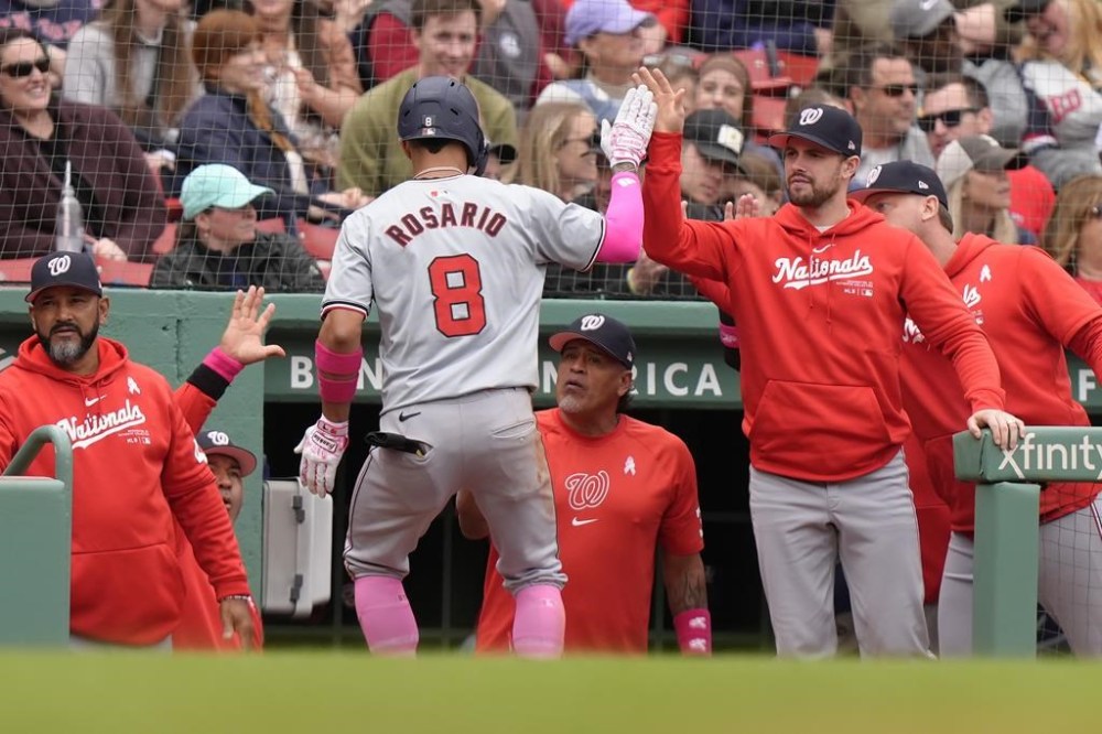 Washington Nationals' Eddie Rosario (8) is welcomed at the dugout after scoring on his two-run home run in the fourth inning of a baseball game against the Boston Red Sox, Sunday, May 12, 2024, in Boston. (AP Photo/Steven Senne)