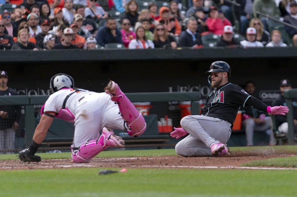 Arizona Diamondbacks catcher Tucker Barnhart, right, slides into home plate as Baltimore Orioles catcher James McCann, left, tries to block during a baseball game Sunday, May 12, 2024, in Baltimore. (AP Photo/Jose Luis Magana)