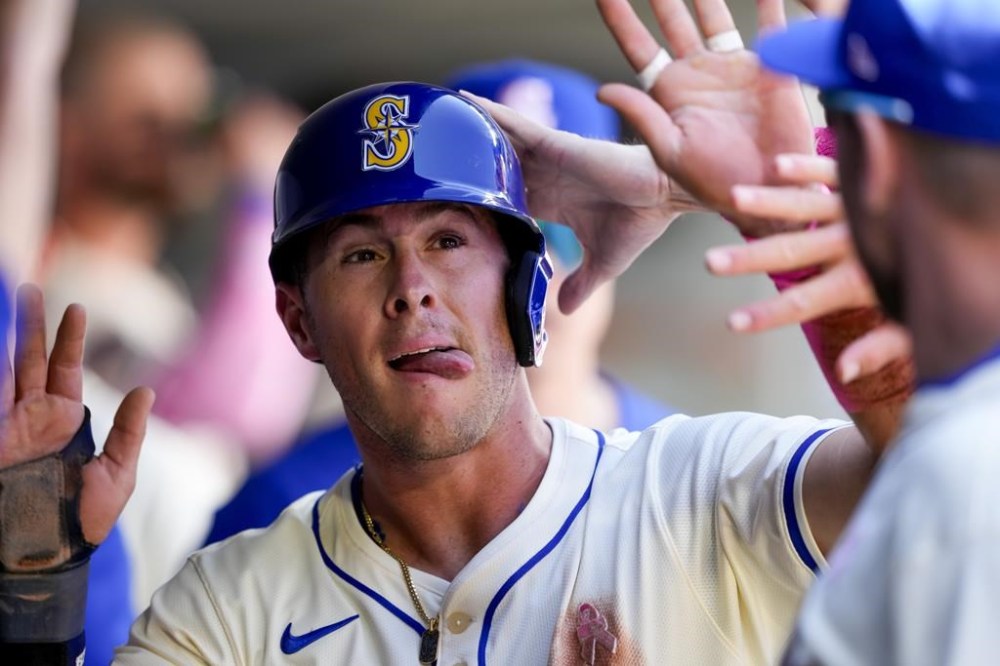 Seattle Mariners' Dylan Moore is greeted in the dugout after scoring on an RBI single from Mitch Garver against the Oakland Athletics during the first inning of a baseball game Sunday, May 12, 2024, in Seattle. (AP Photo/Lindsey Wasson)