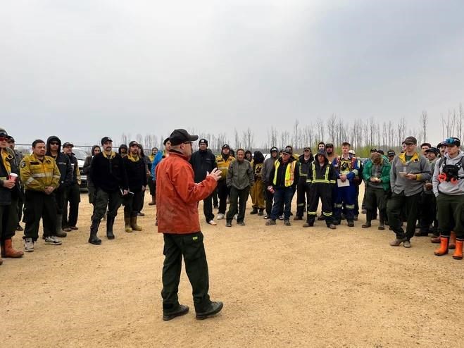 Fire crews battling a blaze outside Fort McMurray are expecting a little help from the weather while crews working a wildfire near Grande Prairie say they expect unfavourable winds and no rain. Crews working to fight a forest fire, designated MWF017 by the Alberta Wildfire Service, are briefed prior to going to work in an unidentified staging area, in a Monday, May 13, 2024, handout photo. THE CANADIAN PRESS/HO-Alberta Wildfire Service, *MANDATORY CREDIT*