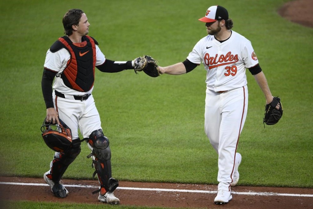 Baltimore Orioles catcher Adley Rutschman, left, and starting pitcher Corbin Burnes, tap gloves as they walk back to the dugout during the middle of the fourth inning of a baseball game against the Toronto Blue Jays, Monday, May 13, 2024, in Baltimore. (AP Photo/Nick Wass)