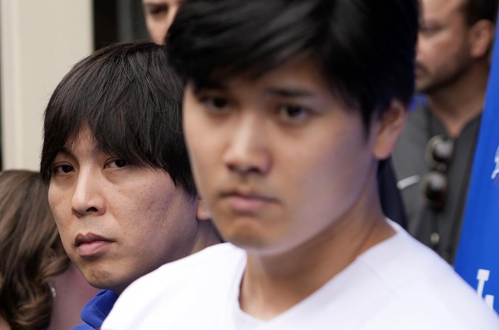 FILE - Interpreter Ippei Mizuhara, left, stands behind Japanese baseball star Shohei Ohtani, front right, and translates during an interview at Dodger Stadium, Feb. 3, 2024, in Los Angeles. Mizuhara, the former interpreter for Los Angeles Dodgers star Ohtani, is expected to plead not guilty Tuesday, May 14, 2024, to bank and tax fraud, a formality ahead of a deal he has negotiated with federal prosecutors in a sports betting case. (AP Photo/Richard Vogel, File)