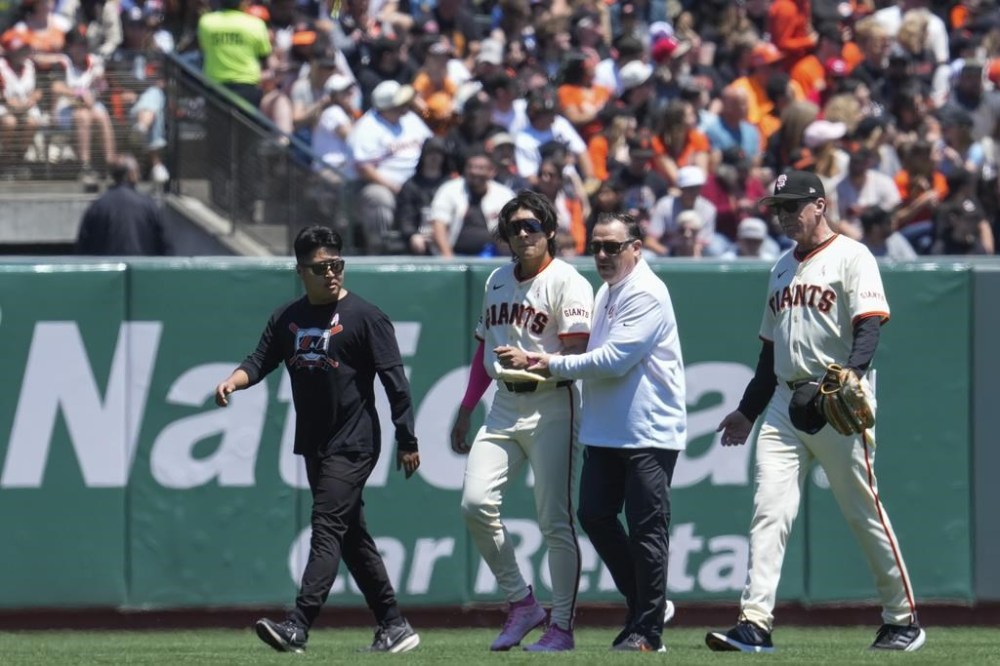 San Francisco Giants center fielder Jung Hoo Lee, second from left, is helped off the field following an injury during the first inning of a baseball game against the Cincinnati Reds, Sunday, May 12, 2024, in San Francisco. (AP Photo/Godofredo A. Vásquez)