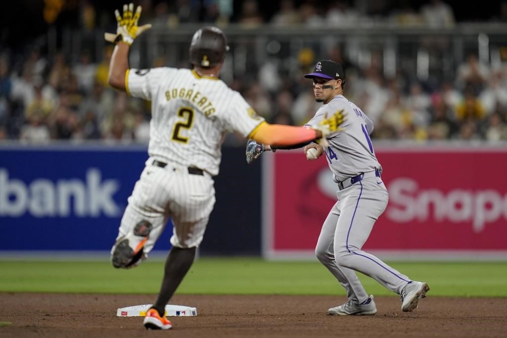 Colorado Rockies shortstop Ezequiel Tovar, right, throws to first too late for a double play as San Diego Padres' Xander Bogaerts is late to second base during the seventh inning of a baseball game, Tuesday, May 14, 2024, in San Diego. (AP Photo/Gregory Bull)