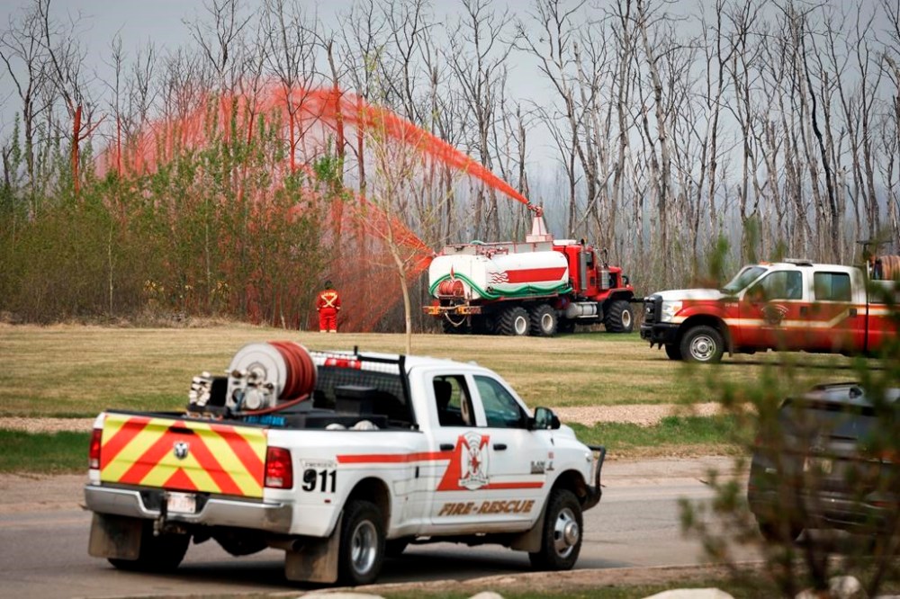 A pumper truck sprays fire retardant on trees around the evacuated neighbourhood of Beacon Hill in Fort McMurray, Alta., on Wednesday, May 15, 2024. THE CANADIAN PRESS/Jeff McIntosh