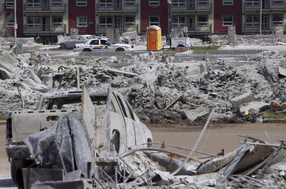 A police car drives through a burnt out Timberlea neighbourhood in Fort McMurray, Alta., on Thursday, June 2, 2016. A fierce wildfire burning outside of Fort McMurray has brought back memories of the vicious blaze, nicknamed The Beast, that tore through the Alberta oilsands hub in 2016. THE CANADIAN PRESS/Jason Franson