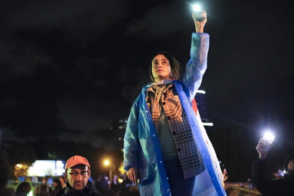 A demonstrator holds up her smart phone with the torch light switched on during an opposition protest against