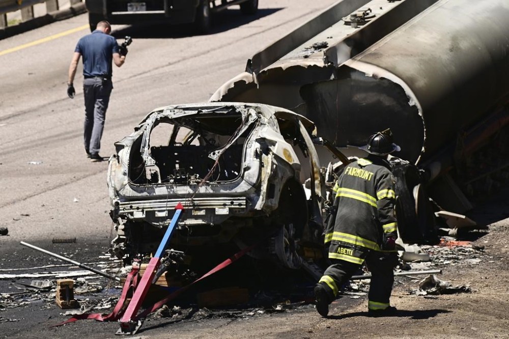 Emergency workers survey the remains of a vehicle after it crashed into the tanker of a truck on Interstate 70, Thursday, May 16, 2024, near Morrison, Colo. The vehicle's driver died and the truck driver was hospitalized from the crash along Colorado's main east-west highway. (Hyoung Chang/The Denver Post via AP)/The Denver Post via AP)