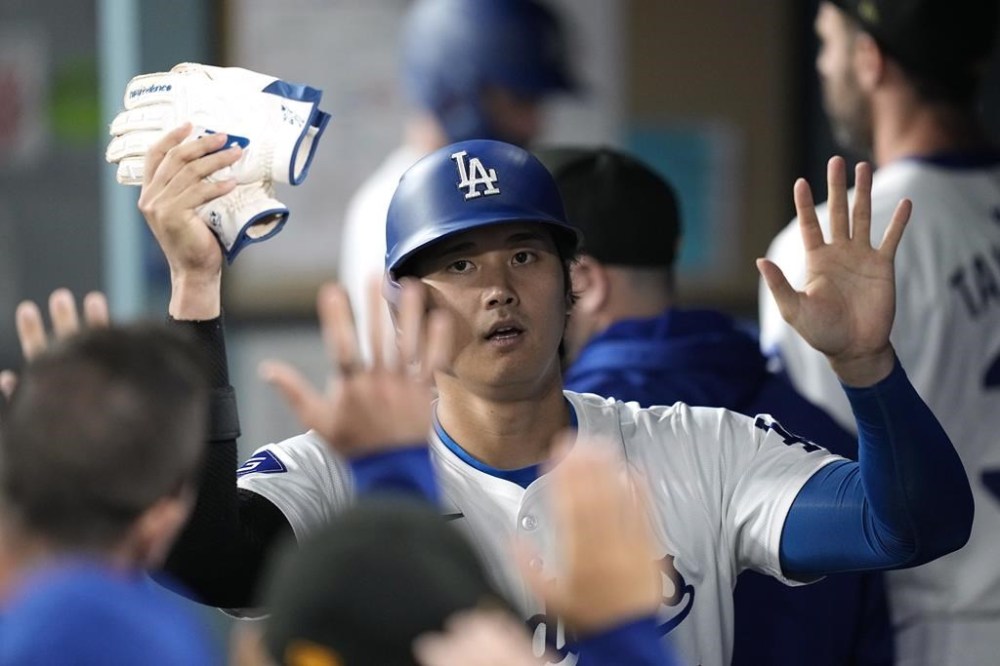 Los Angeles Dodgers' Shohei Ohtani is congratulated by teammates in the dugout after scoring on a single by Will Smith during the seventh inning of a baseball game Friday, May 17, 2024, in Los Angeles. (AP Photo/Mark J. Terrill)