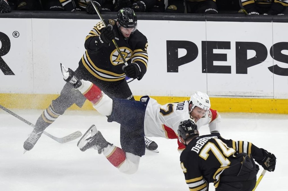 Florida Panthers' Brandon Montour (62) battles Boston Bruins' Morgan Geekie (39) and Jake DeBrusk (74) for the puck during the first period in Game 6 of an NHL hockey Stanley Cup second-round playoff series, Friday, May 17, 2024, in Boston. (AP Photo/Michael Dwyer)