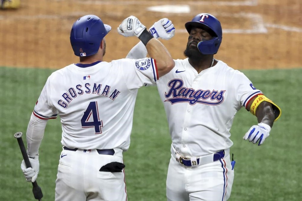 Texas Rangers Robbie Grossman (4) celebrates the home run by Adolis Garcia, right, against the Los Angeles Angels in the sixth inning of a baseball game Saturday, May 18, 2024, in Arlington, Texas. (AP Photo/Richard W. Rodriguez)