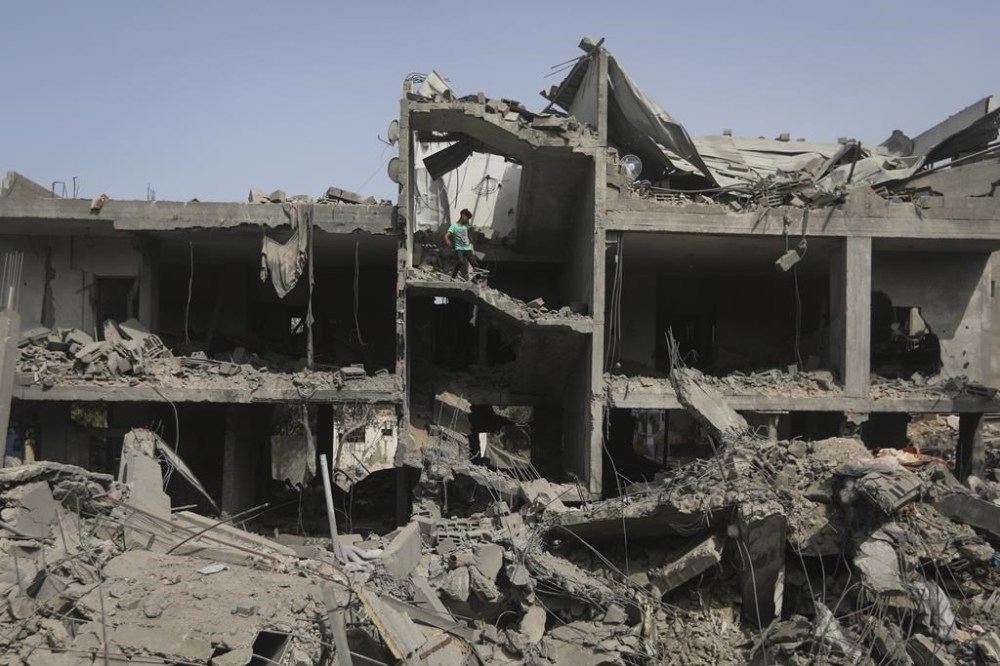 Palestinians look at the destruction after an Israeli strike on a residential building in Nuseirat Refugee Camp, Gaza Strip, Sunday, May 19, 2024. (AP Photo/Ismael Abu Dayyah)