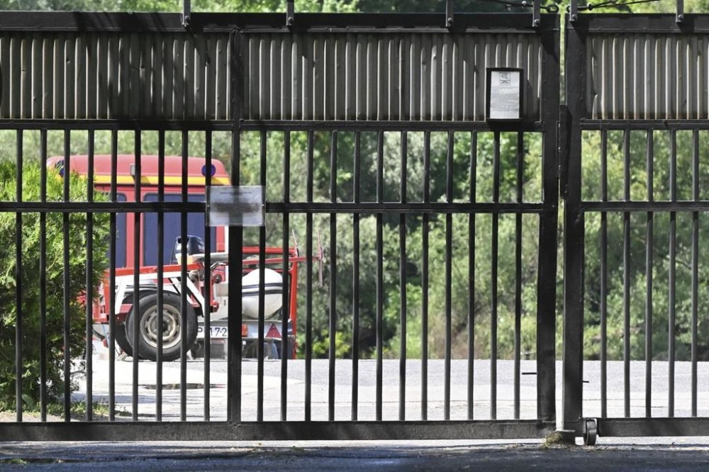 A car of the diving service of the fire brigade is parked behind the closed gate of a military port where rescuers search for victims of a boat accident in Northern Budapest, Hungary, Sunday, May 19, 2024. Last night a motor boat with eight persons onboard crashed with a large river cruise ship on River Danube, north of Budapest. One person has been rescued with serious injuries, two bodies have been recovered and five passengers of the boat are looked for. (Peter Lakatos/MTI via AP)