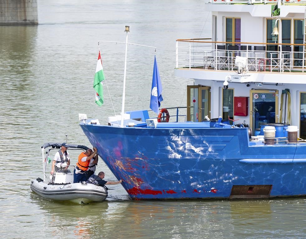 The bow of a river cruise ship is examined by police experts after the ship was stopped in Komarom, Hungary, Sunday, May 19, 2024. Last night the ship crashed with a motor boat with eight persons onboard on River Danube, north of Budapest. One person has been rescued with serious injuries, two bodies have been recovered and five passengers of the boat are being looked for. (Csaba Krizsan/MTI via AP)