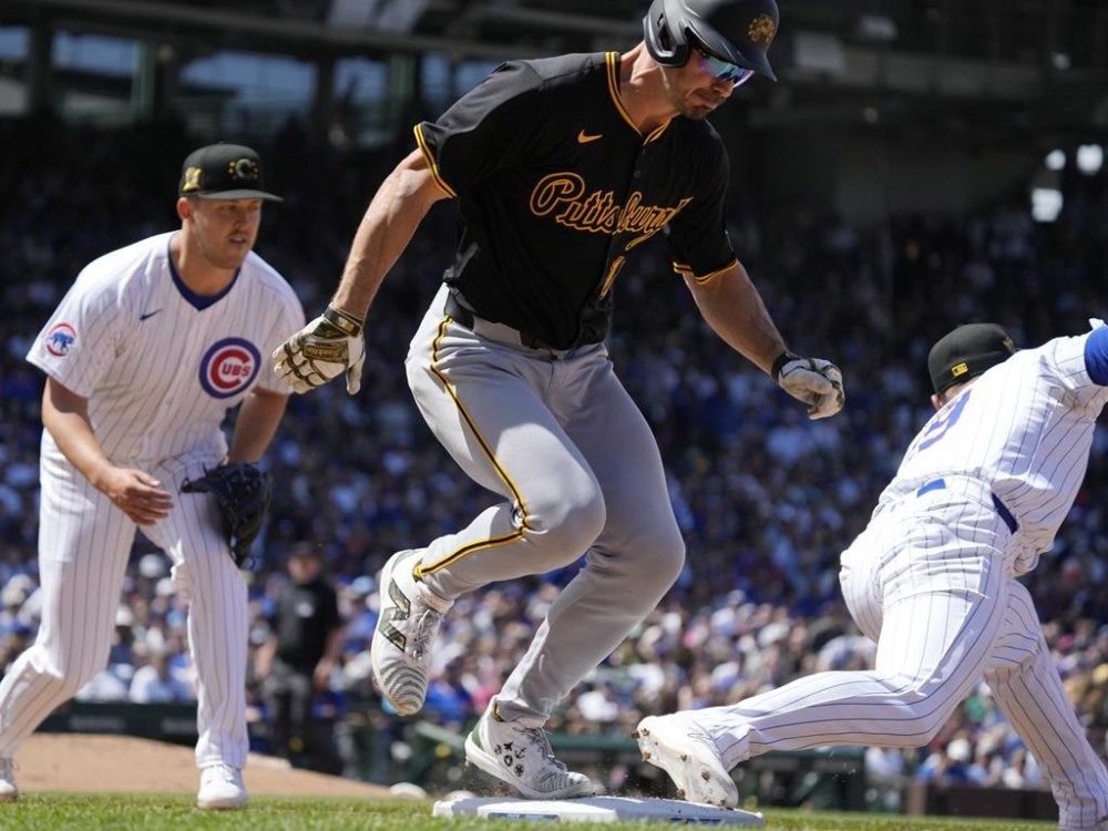 Pittsburgh Pirates' Bryan Reynolds, center, is safe against first baseman Michael Busch, right, at first base after hitting a single as Cubs starting pitcher Jameson Taillon, left, looks on during the fifth inning of a baseball game in Chicago, Sunday, May 19, 2024. (AP Photo/Nam Y. Huh)