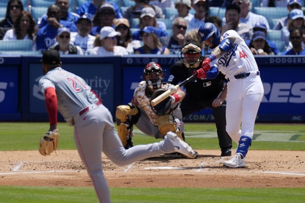Los Angeles Dodgers' Andy Pages, right, hits a two-run home run as Cincinnati Reds starting pitcher Hunter Greene, left, and catcher Luke Maile, second from left, watch along with home plate umpire Chad Whitson during the fourth inning of a baseball game Sunday, May 19, 2024, in Los Angeles. (AP Photo/Mark J. Terrill)
