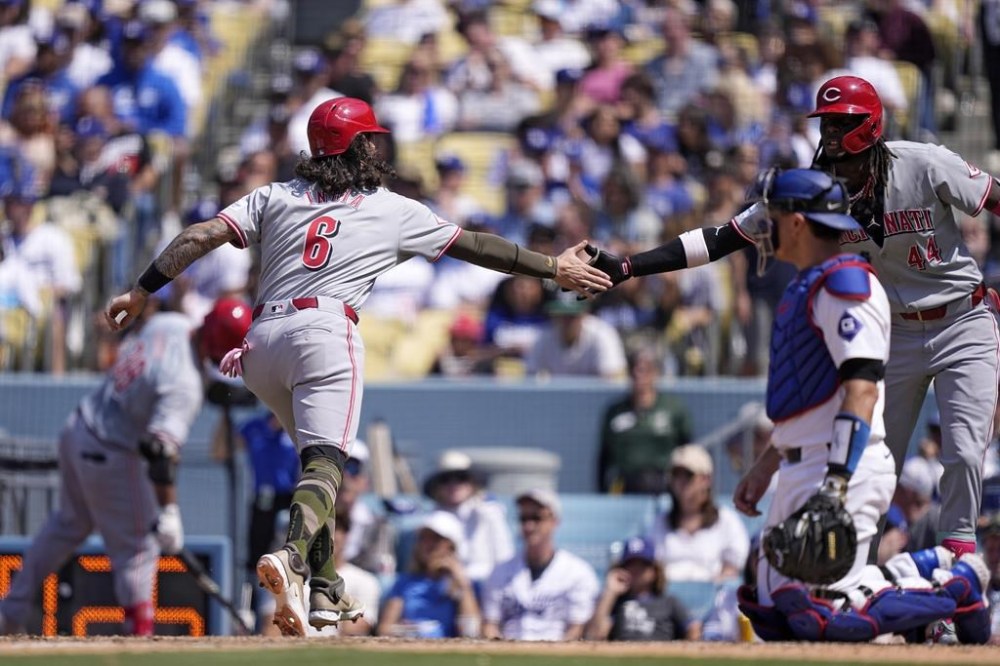 Cincinnati Reds' Jonathan India, left, is congratulated by Elly De La Cruz, right, after scoring on a walk as Los Angeles Dodgers catcher Austin Barnes kneels at the plate during the seventh inning of a baseball game Sunday, May 19, 2024, in Los Angeles. (AP Photo/Mark J. Terrill)