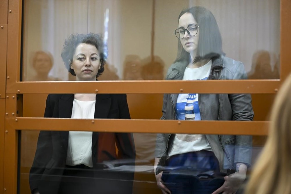 Theater director Zhenya Berkovich, left, and playwright Svetlana Petriychuk are seen in a glass cage prior to a hearing in a court in Moscow, Russia, Monday, May 20, 2024. Berkovich, a prominent independent theater director, and Petriychuk, a playwright have been behind bars since early May. Authorities claim a play they staged,