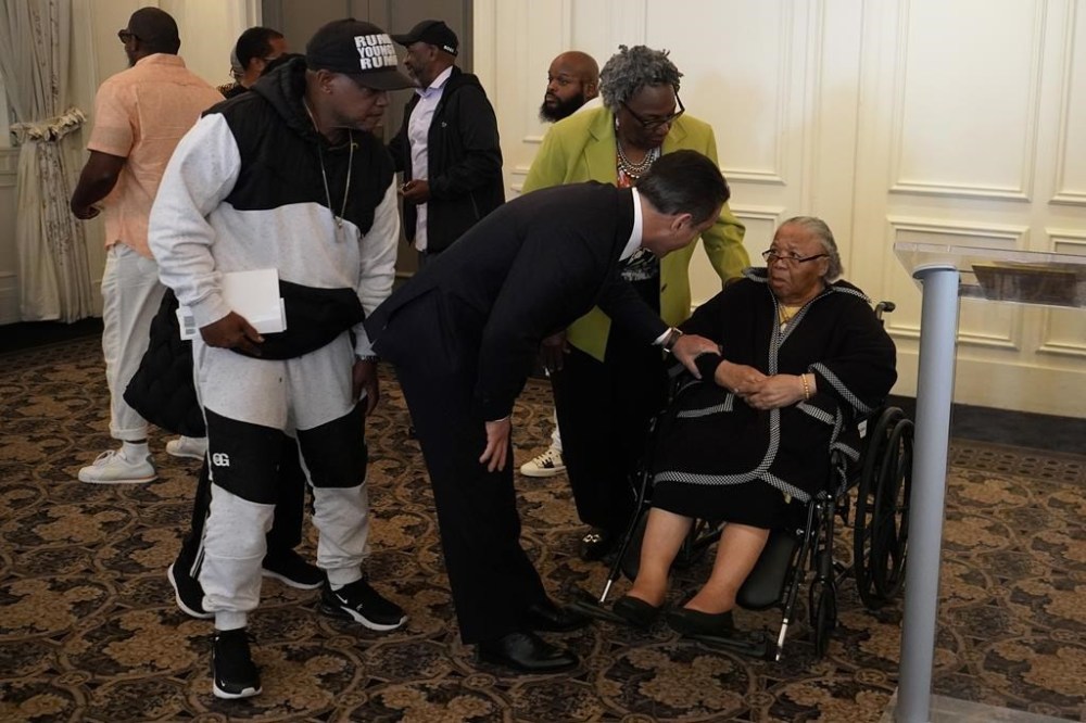 Lawyer Joseph Marrone, lower center, greets Susie Williams Carter, right, after a news conference, Monday, May 20, 2024, in Philadelphia. Carter, the sister of the youngest person ever executed in the state of Pennsylvania, Alexander McClay Williams, 16, is suing the county where the Black teenager was convicted in 1931. The suit comes two years after Williams' conviction by an all-white jury was vacated. (AP Photo/Matt Slocum)