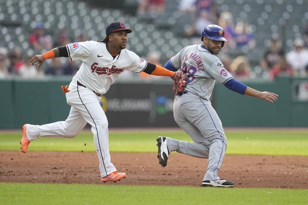 Cleveland Guardians third base José Ramírez, left, tags out New York Mets' J.D. Martinez, right, between second and third base in the second inning of a baseball game Monday, May 20, 2024, in Cleveland. (AP Photo/Sue Ogrocki)