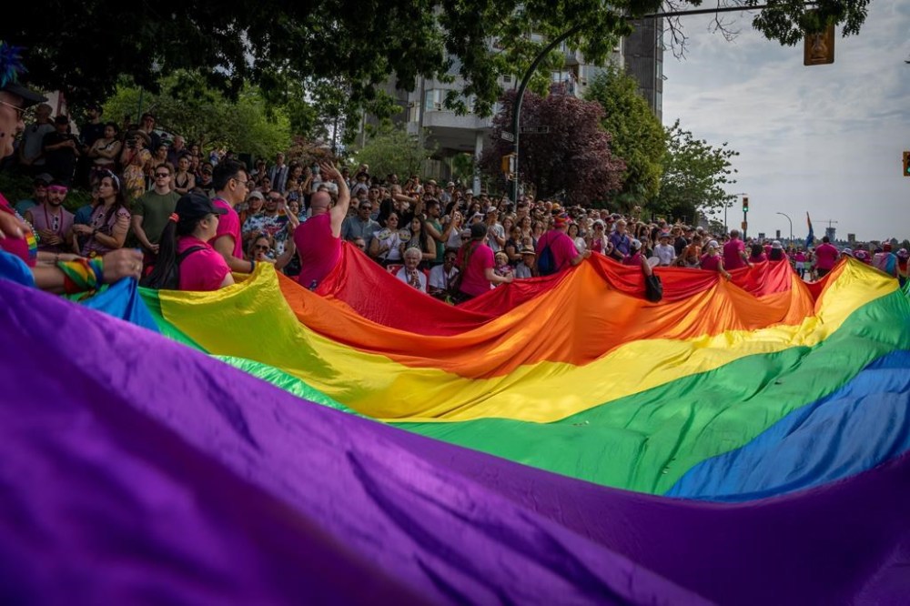 An Alberta queer community organizer says a ban on United Conservative Party MLAs attending pride events across the province this summer aims to pressure the government until its policies match its rhetorical support for trans and queer people. A large pride flag is passed along during the Pride Parade at English Bay in Vancouver, Sunday, Aug. 6, 2023. THE CANADIAN PRESS/Ethan Cairns