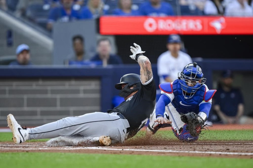 Chicago White Sox's Korey Lee (26) slides in to home ahead of the tag from Toronto Blue Jays catcher Danny Jansen (9) attempts to make a tag during second inning MLB baseball action in Toronto on Tuesday, May 21, 2024. THE CANADIAN PRESS/Christopher Katsarov