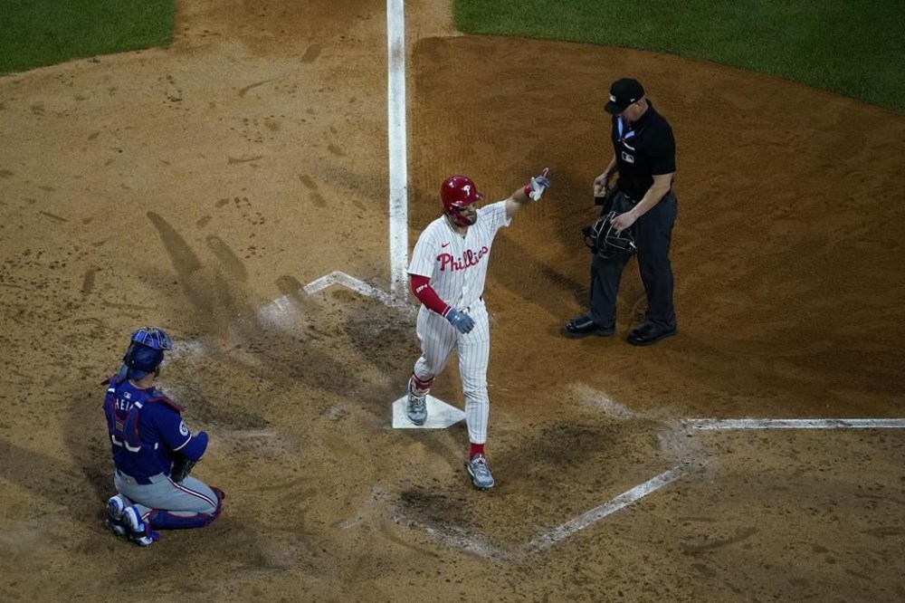Philadelphia Phillies' Bryce Harper, center, reacts after hitting a home run against Texas Rangers pitcher Jacob Latz during the sixth inning of a baseball game, Tuesday, May 21, 2024, in Philadelphia. (AP Photo/Matt Slocum)