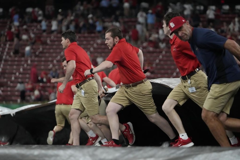 Members of the Busch Stadium grounds crew rush to unfurl the tarp as a storm approaches at the start of a rain delay during the sixth inning of a baseball game between the St. Louis Cardinals and the Baltimore Orioles Tuesday, May 21, 2024, in St. Louis. (AP Photo/Jeff Roberson)