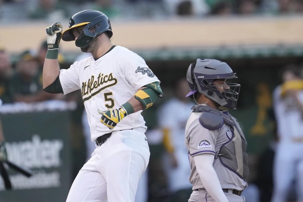 Oakland Athletics' J.D. Davis (5) reacts after hitting a home run next to Colorado Rockies catcher Elias Díaz during the third inning of a baseball game in Oakland, Calif., Tuesday, May 21, 2024. (AP Photo/Jeff Chiu)