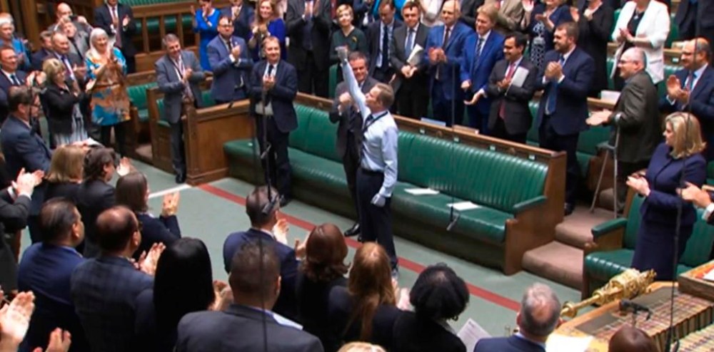 Craig Mackinlay, Conservative MP for South Thanet, is applauded by members of parliament as he returns to the House of Commons for the first time since he was rushed into hospital with sepsis on September 28, which left him with both of his hands and feet amputated, at the Parliament in London, Wednesday May 22, 2024. (House of Commons/UK Parliament via AP)