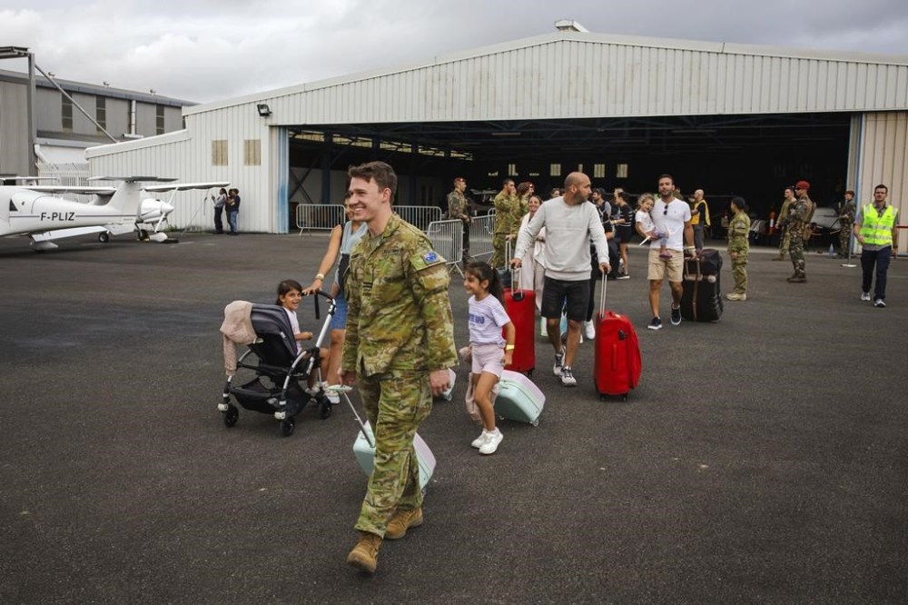 In this photo provided by the Australian Defence Force, Royal Australian Air Force Officer, Flight Lieutenant Thomas Rogers, second left, assists Australian and other tourists to a waiting plane for departure from Noumea, New Caledonia, Tuesday, May 21, 2024. The Australian military had flown 115 passengers in two flights from the restive French Pacific territory of New Caledonia and would continue to work with France to repatriate all Australians who want to leave, an Australian government minister said Wednesday, May 22, 2024. (LAC Adam Abela/ADF via AP)