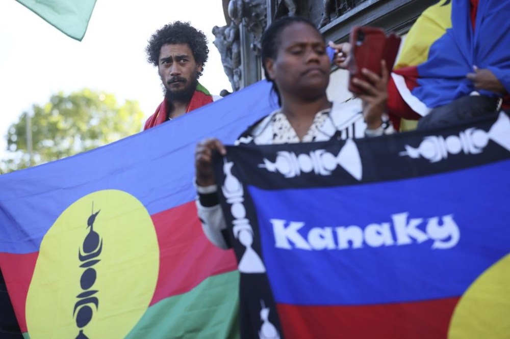 Demonstrators hold Kanak and Socialist National Liberation Front (FLNKS) flags during a gathering in Paris, Thursday May.16, 2024. Violence raged across New Caledonia for the third consecutive day Thursday, hours after France imposed a state of emergency in the French Pacific territory, boosting security forces' powers to quell unrest in the archipelago that has long sought independence. (AP Photo/Thomas Padilla)